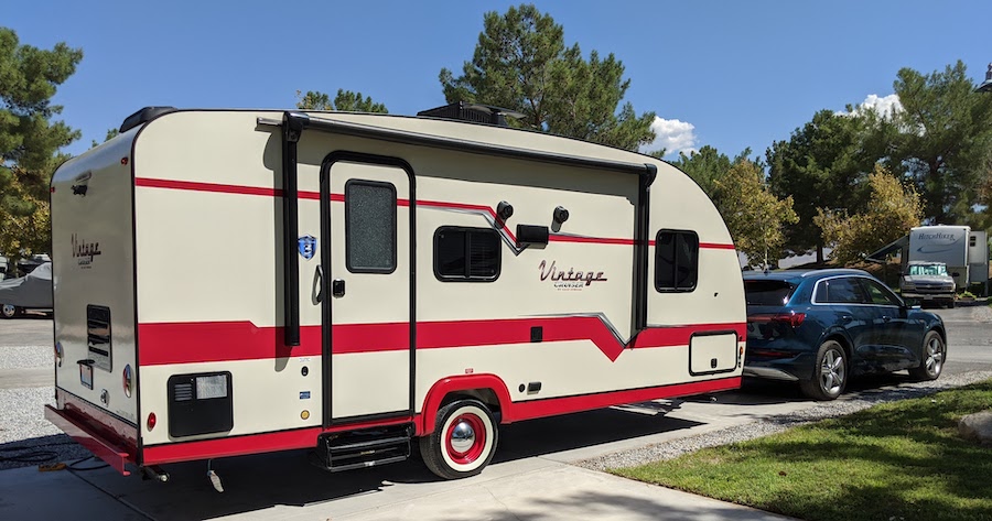 Vintage trailer parked at campground behind electric vehicle