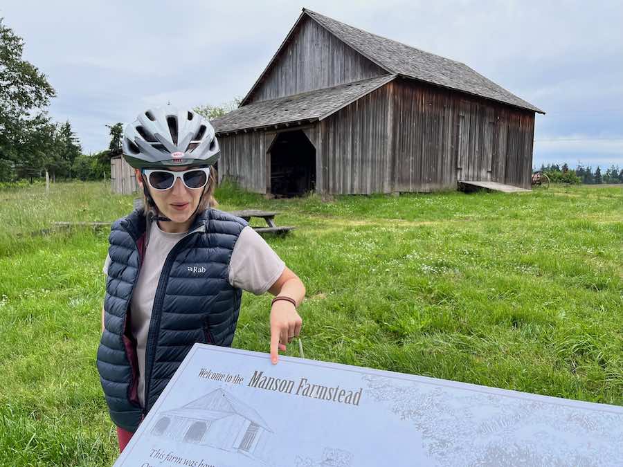 author pointing at sign in front of historic barn